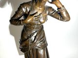 bronze statue of a woman holding a bird on her head