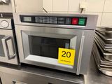 un micro-ondes sur lequel est collé un autocollant jaune, dans une cuisine