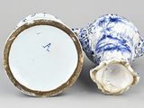 a blue and white vase sitting next to a white and gold vase