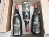 three bottles of wine in a cardboard box on the floor