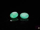 two pieces of green jade are sitting on a black surface