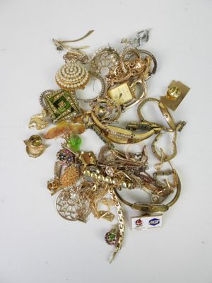a pile of gold and silver jewelry on a white surface