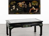 une table basse orientale avec un plateau en verre et un tableau accroché au mur