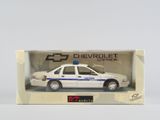 Une voiture de police Chevrolet Caprice dans une boîte, posée sur une surface blanche