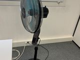 a fan that is sitting on a stand in a room