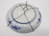 une assiette bleue et blanche entourée d'un fil métallique