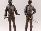 pair of bronze figurines of a man and a woman holding swords