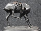 sculpture of antelope standing on a marble base on a black background