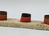 three small red and black pots on top of a piece of wood