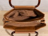 leather handbag on a wooden table with a white wall in the background