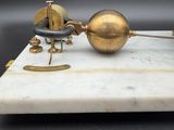 an antique brass and marble clock with a pendulum on a marble base