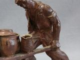 a figurine of a man sitting on a wheelbarrow with pots on it