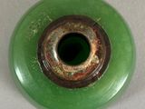 a green vase with a hole in it on a table