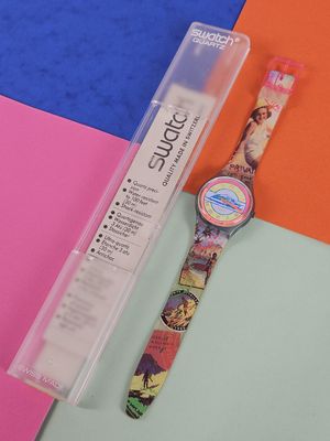 a watch sitting on a colorful surface next to a toothbrush