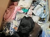 a box full of clothes and a cat laying on the floor