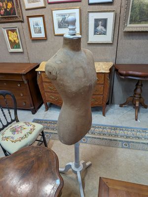 a mannequin on a stand in a room with pictures on the wall