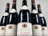 six bottles of red wine lined up in a row on a table