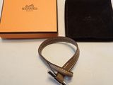 La ceinture en cuir marron se trouve à côté d'une boîte orange et d'un portefeuille noir
