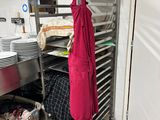a red apron hanging on a rack in a kitchen
