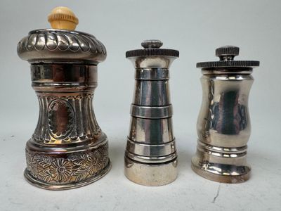 trois salières et poivrières en argent posées les unes à côté des autres sur une table