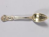 a silver spoon with a handle on a white surface