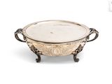 une assiette en argent ancienne avec des poignées et des poignées sur un support