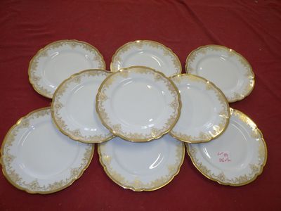 six white and gold plates with gold trim on a red table cloth