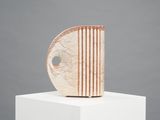 an abstract sculpture on a white pedestal with a gray background