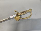 a gold sword with a gold handle on a white surface