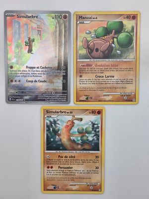 Trois cartes Pokémon sont représentées sur une surface blanche