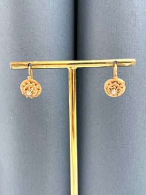une paire de boucles d'oreilles en or sur un présentoir plaqué or