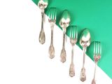 five silver spoons and a fork on a green and white background