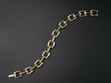 gros plan d'un bracelet en chaîne en or sur une surface noire