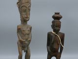 two wooden statues of a man and a woman with a vase on their head