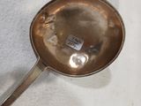 une cuillère en argent avec un manche, posée sur une nappe blanche
