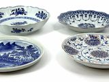 four blue and white bowls with designs on them on a white surface