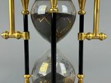 an image of a gold and black hourglass sitting on top of a wooden base