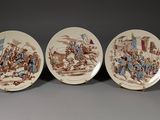 three brown and white plates with pictures of people on them