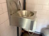 a stainless steel sink in the corner of a public restroom