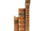 several old books are stacked on top of each other on a white surface