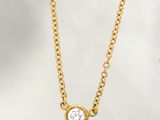 a gold necklace with a white diamond on a chain