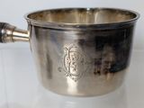 a silver cup with a handle on a glass table