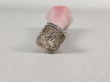 a small silver stamp with a monogram on it