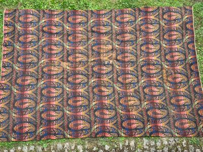 Un vieux tapis est posé par terre, dans l'herbe.