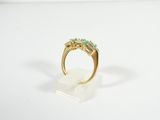 a close up of a gold ring with three emerald stones