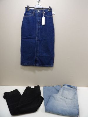 deux paires de jeans bleus et une paire de bottes noires posées sur une table blanche