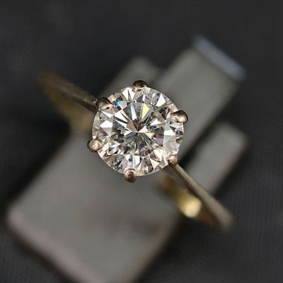 un gros plan d'une bague en diamant posée sur un bloc de marbre