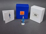 a small figurine of a man standing next to a blue box