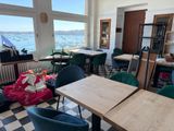 tables and chairs in a room with a view of the water