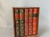 trois livres dans un coffret en bois posé sur une surface blanche